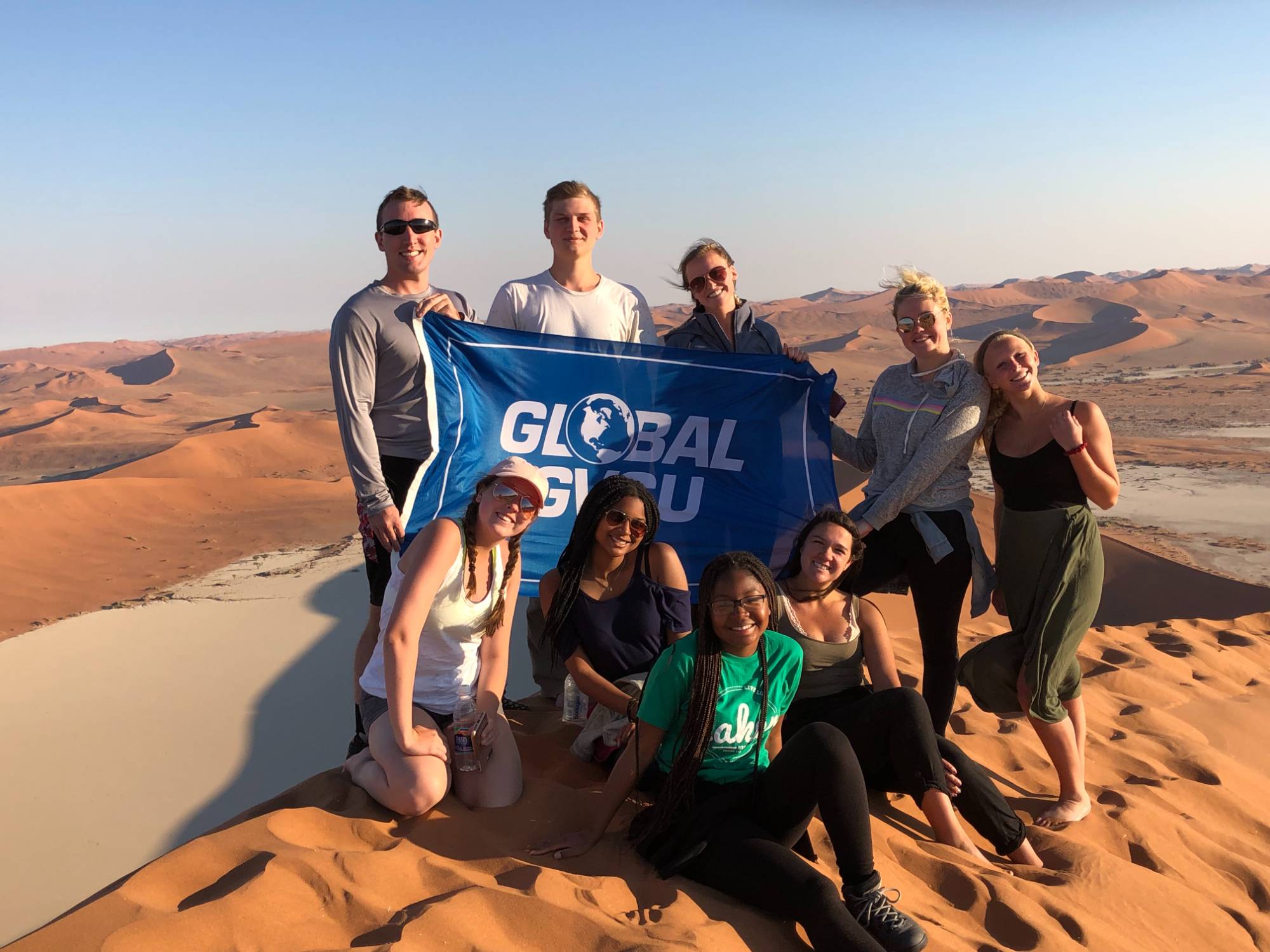Students holding a flag at the dunes in Namibia